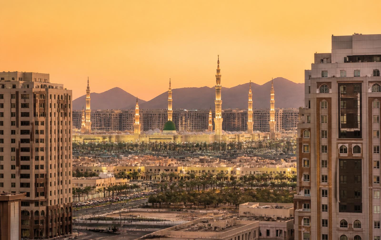 Madinah skyline at golden hour with residential towers and the Prophet's Mosque minarets